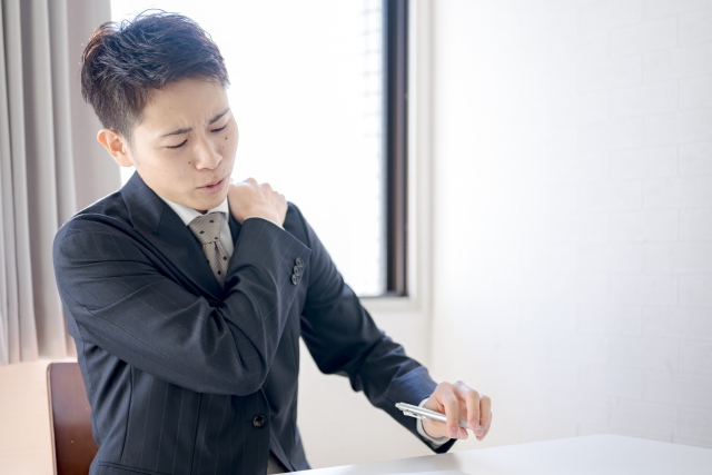 肩に手を当てるオフィスワーカー 姿勢が悪くなりがちな仕事